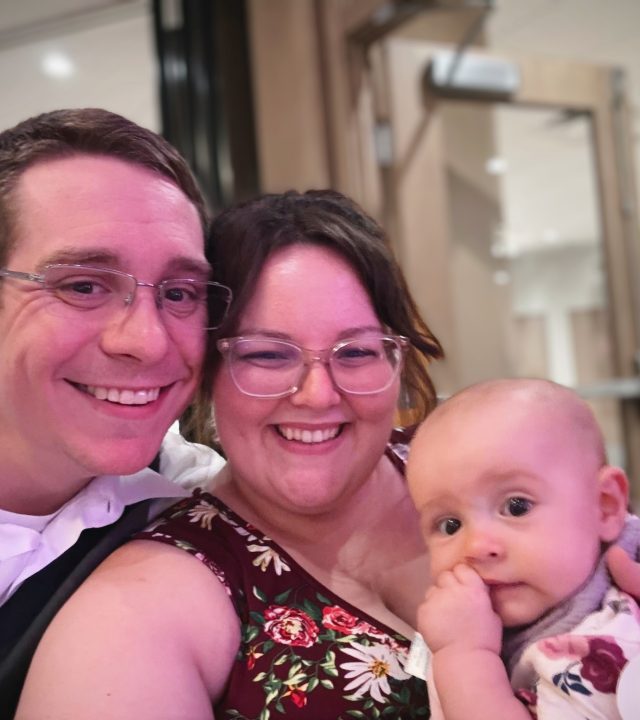 Father, mother, and baby pose smiling for photo